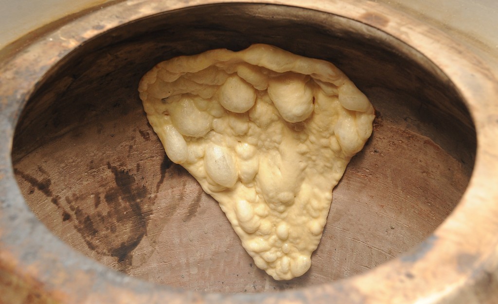 Traditional cooking of naan bread in a clay oven